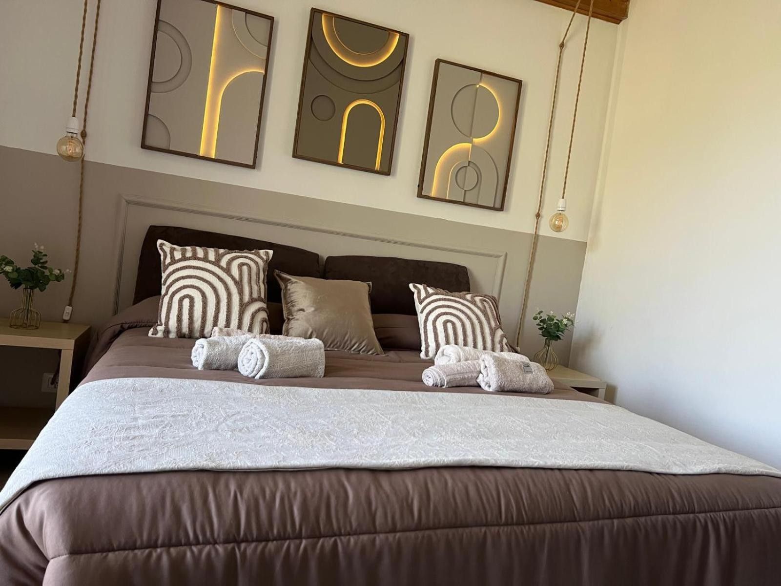 A neatly made bed with a brown headboard, multiple pillows, and a white blanket.