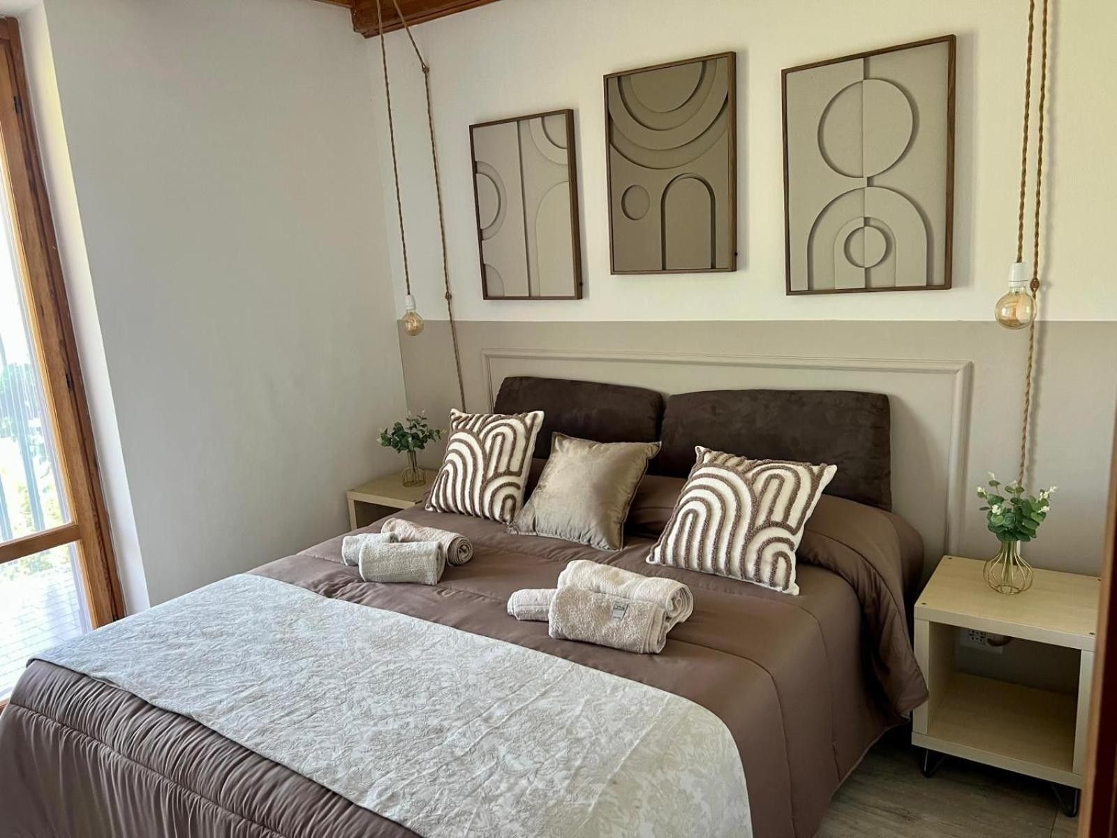 A bedroom with a large bed, two bedside tables, and three wall-mounted artworks.