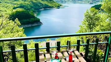 A wooden deck with a view of a lake surrounded by hills.