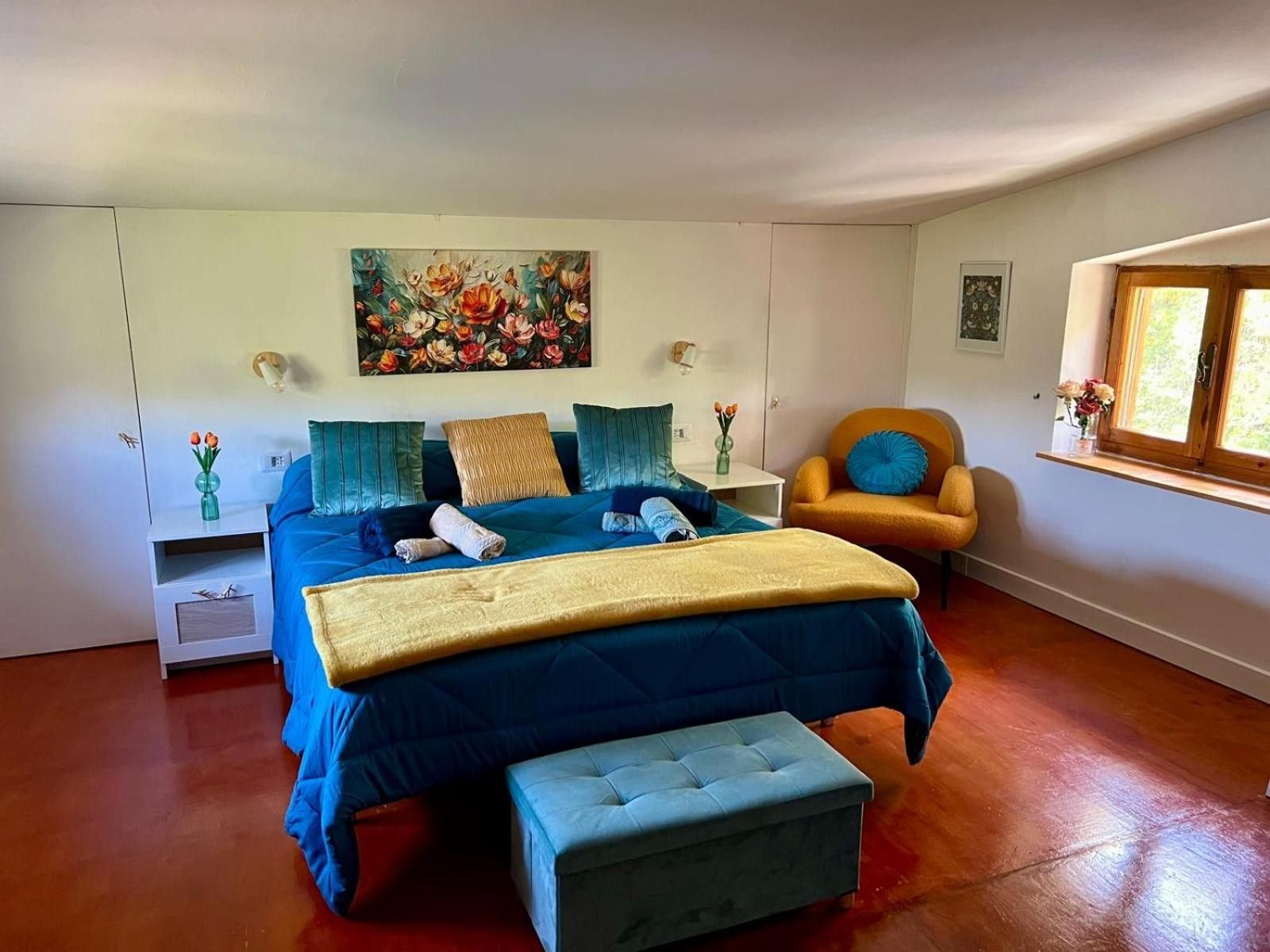 Una camera da letto con un letto grande, una sedia, un quadro e una finestra.