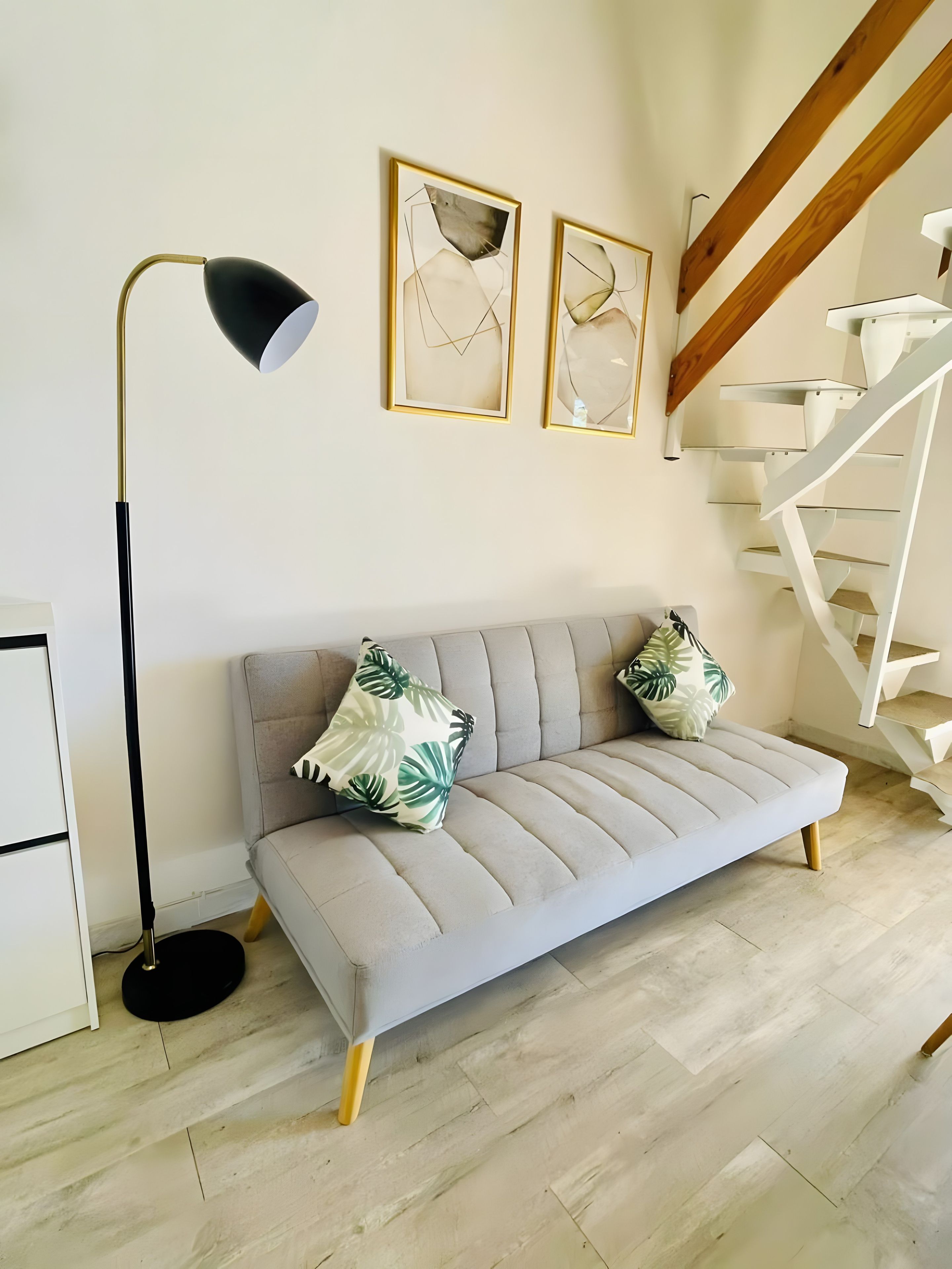 A modern living room with a sofa, a floor lamp, and a spiral staircase.