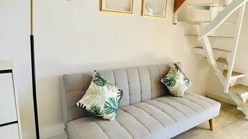 A modern living room with a sofa, a floor lamp, and a spiral staircase.