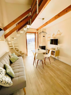 Un ambiente moderno con una scala, un divano, un tavolo da pranzo e una TV.