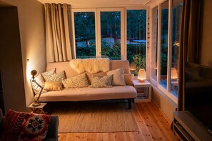 A cozy living room with a sofa, cushions, a rug, a side table with a lamp, and a TV. - A Swedish-style house with a sunny wooded garden, located near Lake Stechlin and Lake Dagow. (Stechlin)