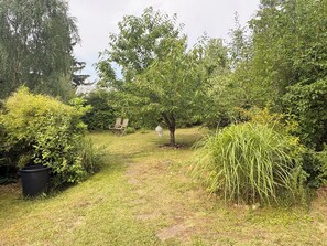 A garden with a pathway, a wooden bench, and various shrubs. - A Swedish-style house with a sunny wooded garden, located near Lake Stechlin and Lake Dagow. (Stechlin)