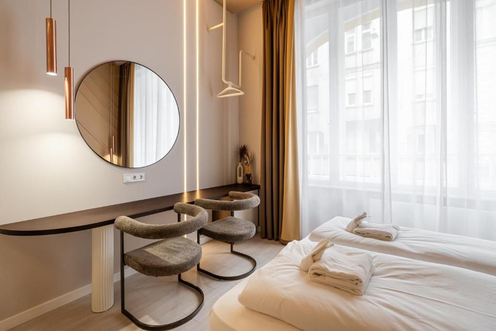 Een hotelkamer met een bed, een ronde spiegel, een krabpaal voor een kat en een raam met gordijnen.