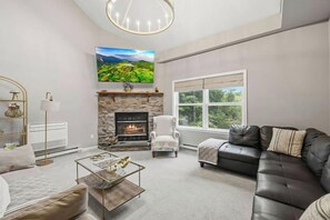 A modern living room with a fireplace, a sofa, a coffee table, and a television mounted on the wall. - Lakeview Retreat | Theater, Games & 140 Acres (Monticello)