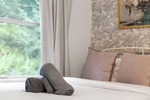 A neatly made bed with pillows, a window with curtains, and a wall with a framed picture. - Lakeview Retreat | Theater, Games & 140 Acres (Monticello)