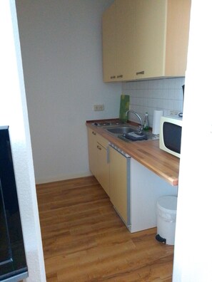 Una cocina funcional con piso de madera, lavavajillas integrado y microondas.