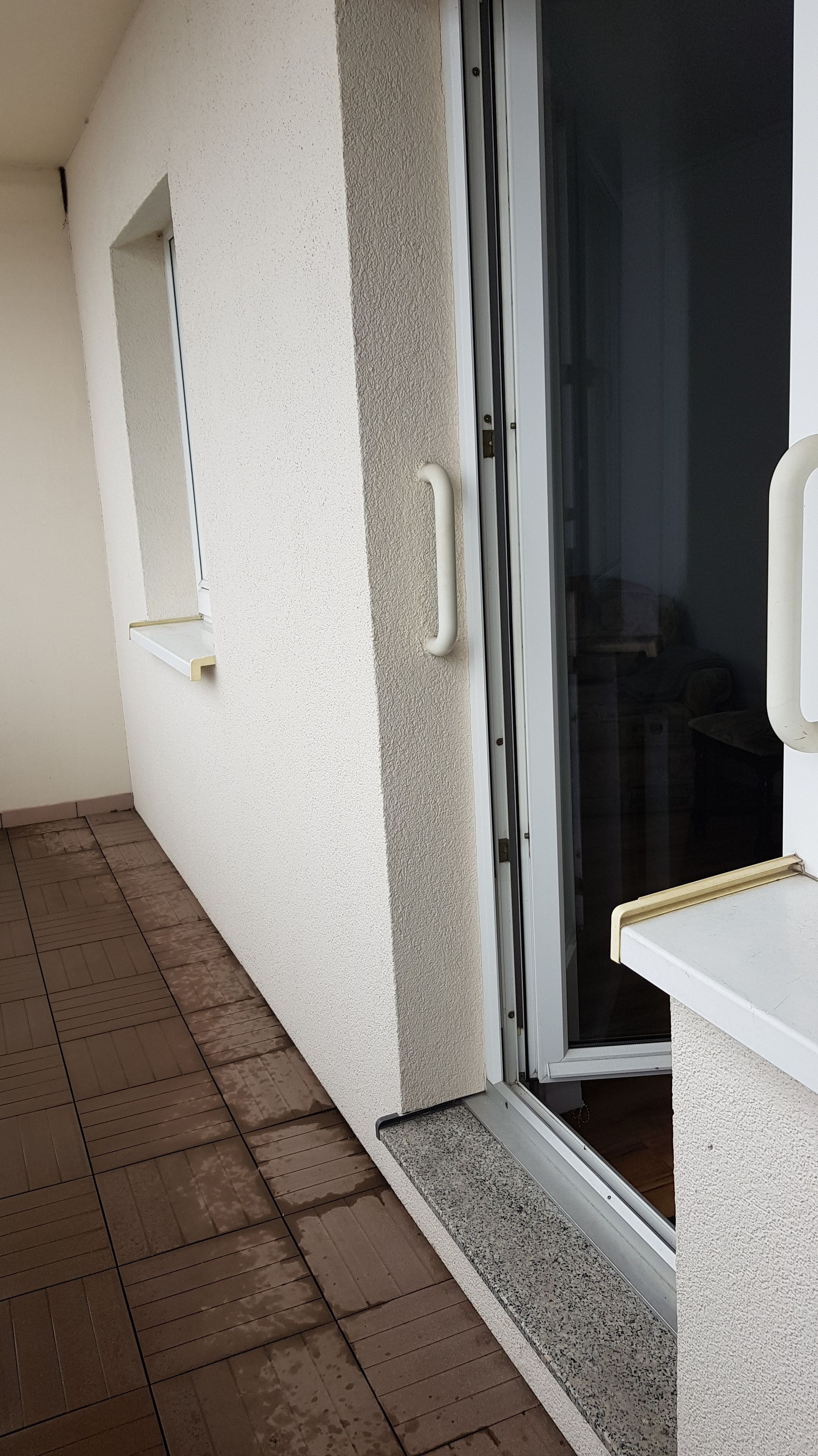 A corridor with a sliding glass door leading to a room, a small window, and a white counter.