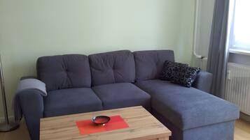 A modern living room with a sectional sofa, a wooden coffee table, and a radiator.