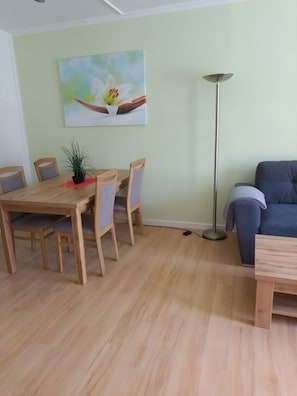 Un comedor con una mesa y sillas de madera, una planta en maceta y un cuadro en la pared.