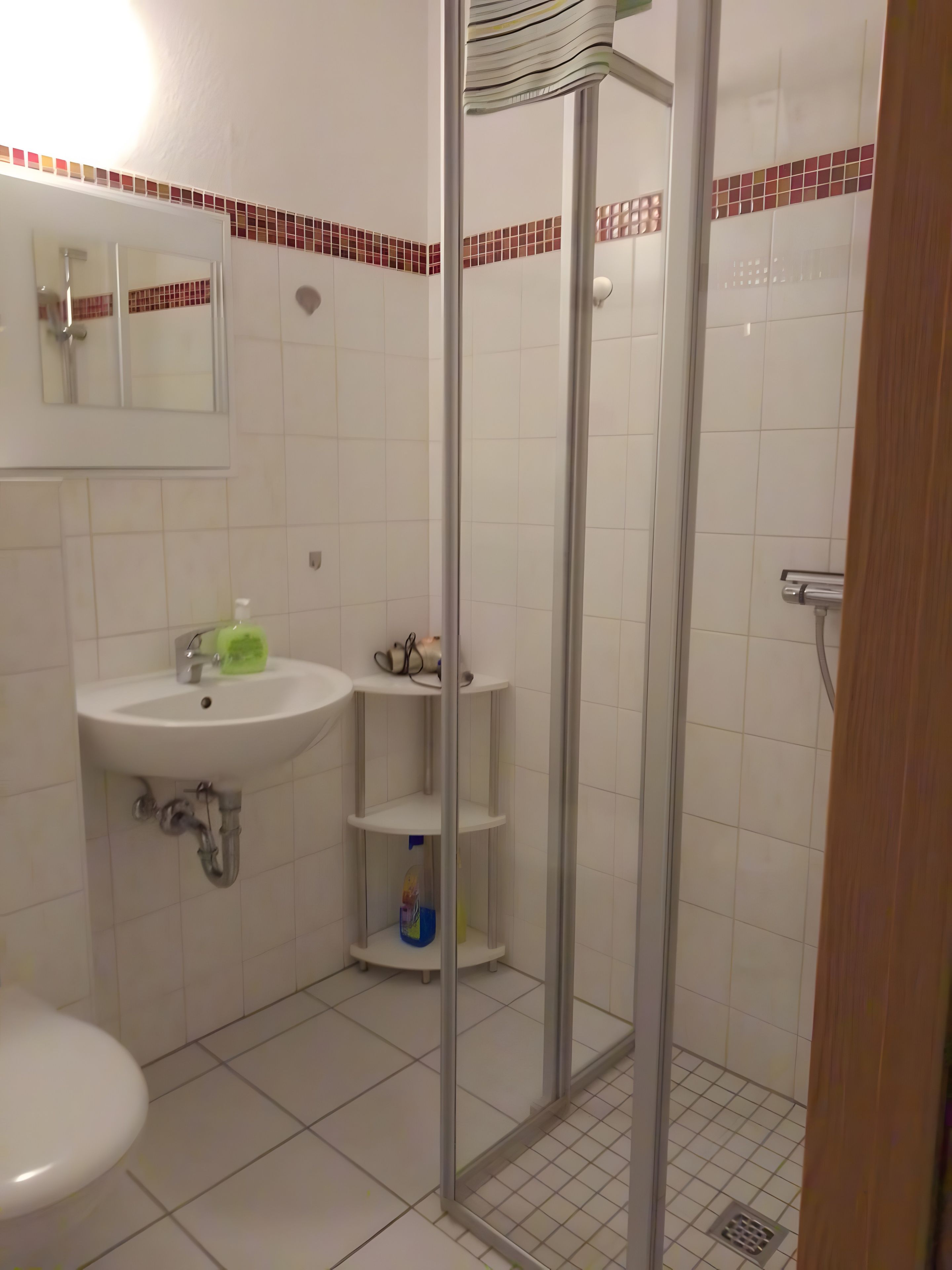 Ein Badezimmer mit Waschbecken, Spiegel, Toilette und einer Duschkabine.