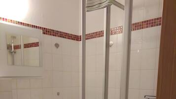 Ein Badezimmer mit Waschbecken, Spiegel, Toilette und einer Duschkabine.