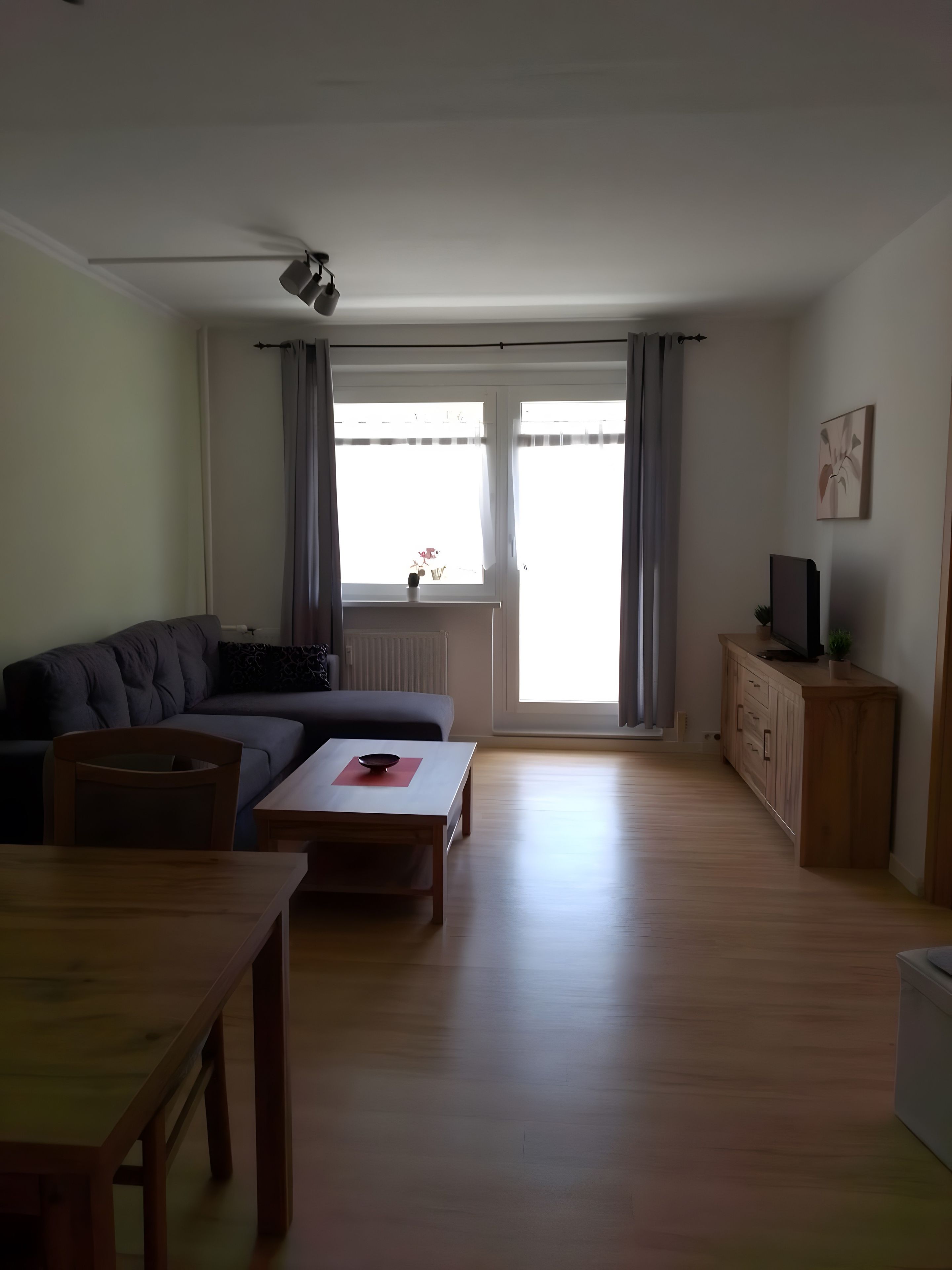 A living room with a sofa, a coffee table, a TV on a cabinet, and a ceiling fan.