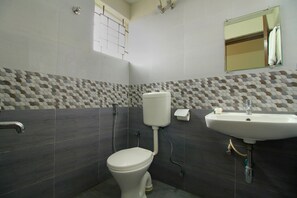 A bathroom with a toilet, sink, and a window with a view. - Hotel O Manu Residency (Bangalore)