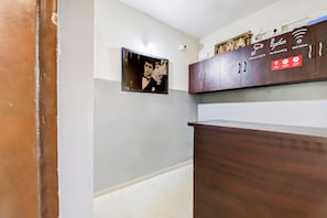 A hallway with a wooden cabinet, a framed picture, and a CCTV camera. - Hotel O Manu Residency (Bangalore)
