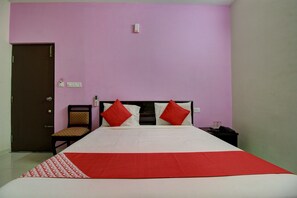 A hotel room with a bed, a chair, a nightstand, and a door. - Hotel O Manu Residency (Bangalore)