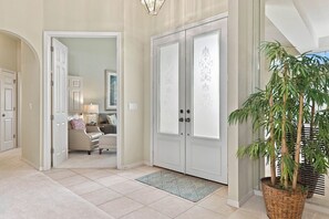A hallway with a door leading to a living area, a potted plant, and a patterned rug. - Lakeview home with Golf - 5 Minutes to Gulf Beaches (Bonita Springs)