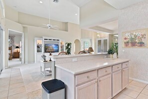 A spacious kitchen with a central island, white cabinetry, and a ceiling fan. - Lakeview home with Golf - 5 Minutes to Gulf Beaches (Bonita Springs)