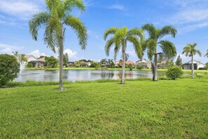 A residential area with a lake, palm trees, and houses. - Lakeview home with Golf - 5 Minutes to Gulf Beaches (Bonita Springs)