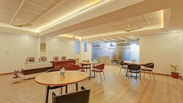 Un espace repas moderne avec des tables et des chaises rondes, un plancher en bois et des ventilateurs de plafond.