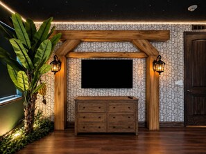 Ein Zimmer mit Steinwand, einer hölzernen Bank und einem angebrachten Fernseher.