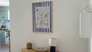 Una habitación con una consola de madera, una lámpara y una obra de arte enmarcada en la pared.