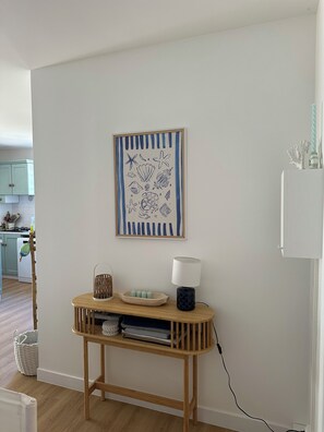 A room with a wooden console table, a lamp, and a framed artwork on the wall. - Vrbo Property (Saint-Pierre-d'Oléron)