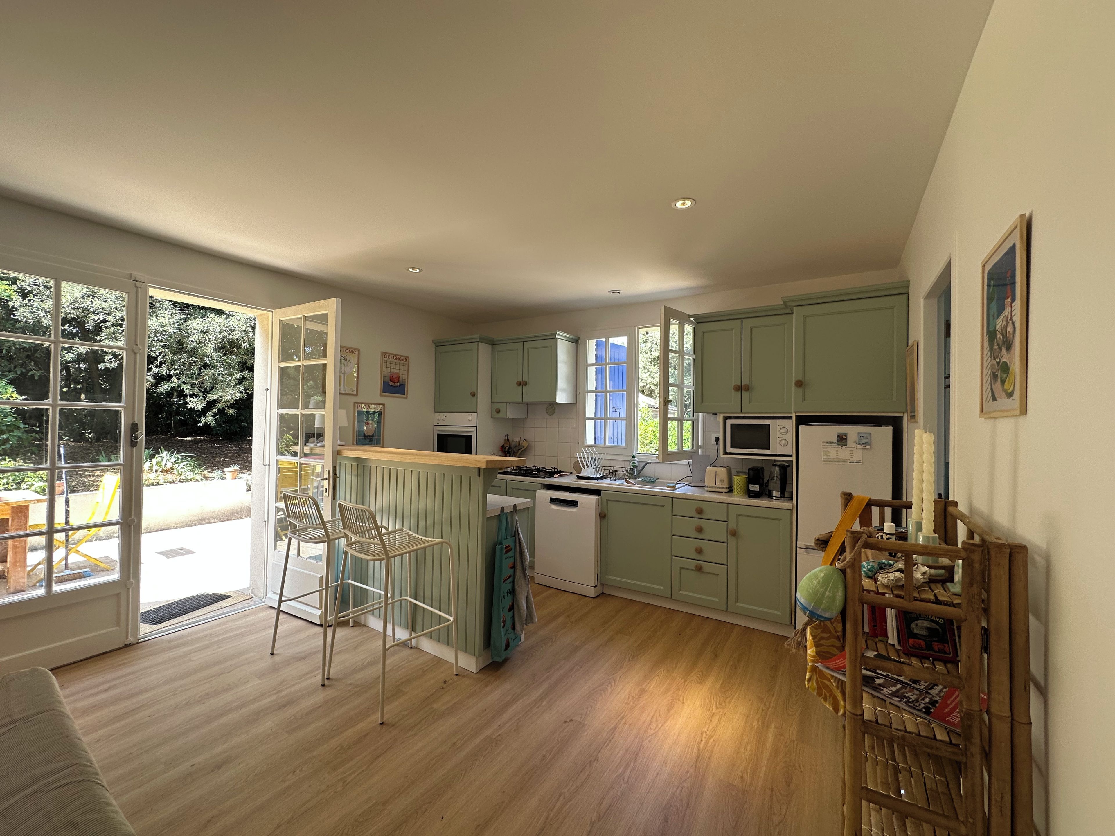 A kitchen with a dining area, wooden flooring, and a view of the outdoors.