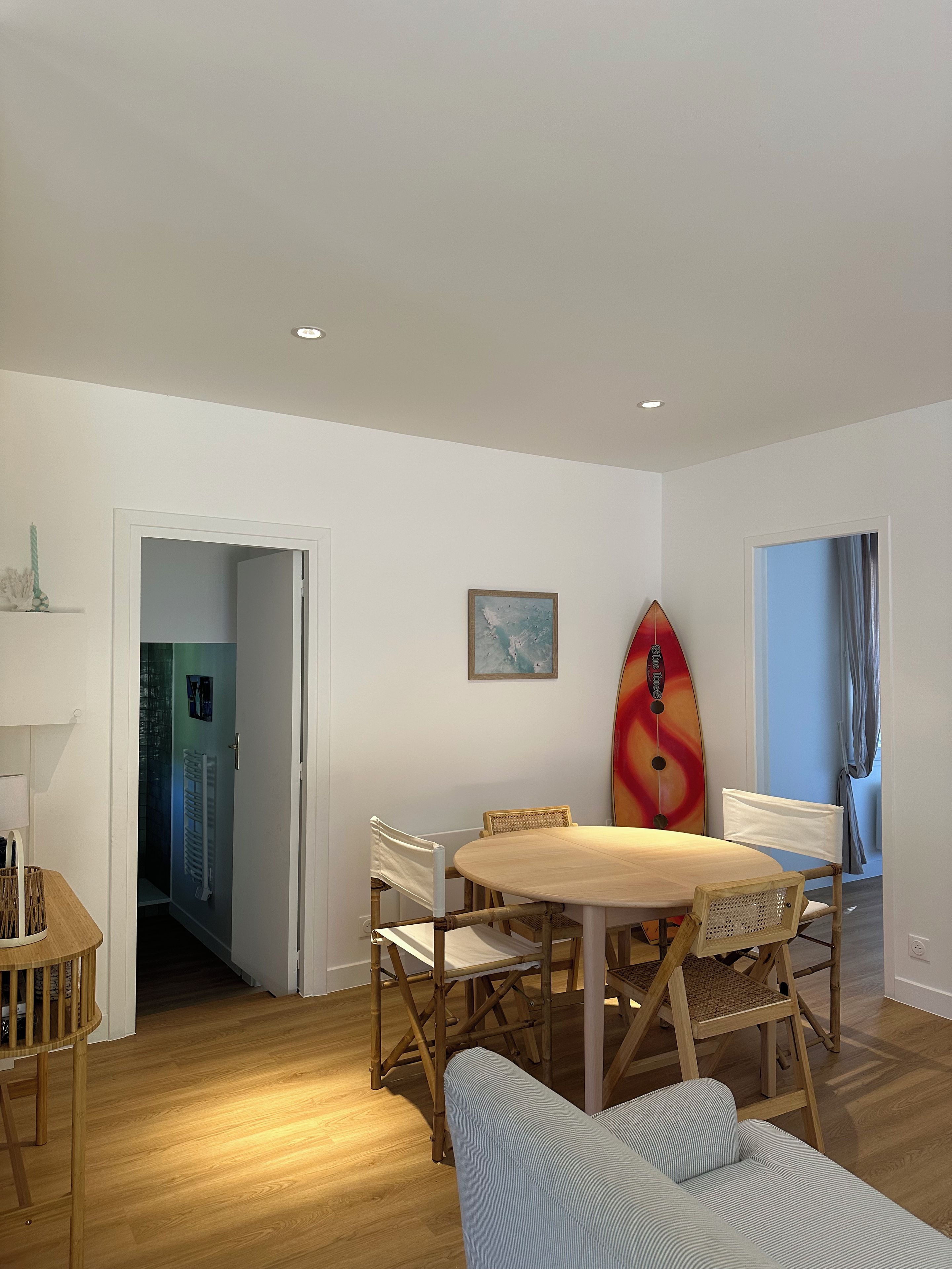 Un comedor con una mesa redonda, sillas y una decoración con una tabla de surf.