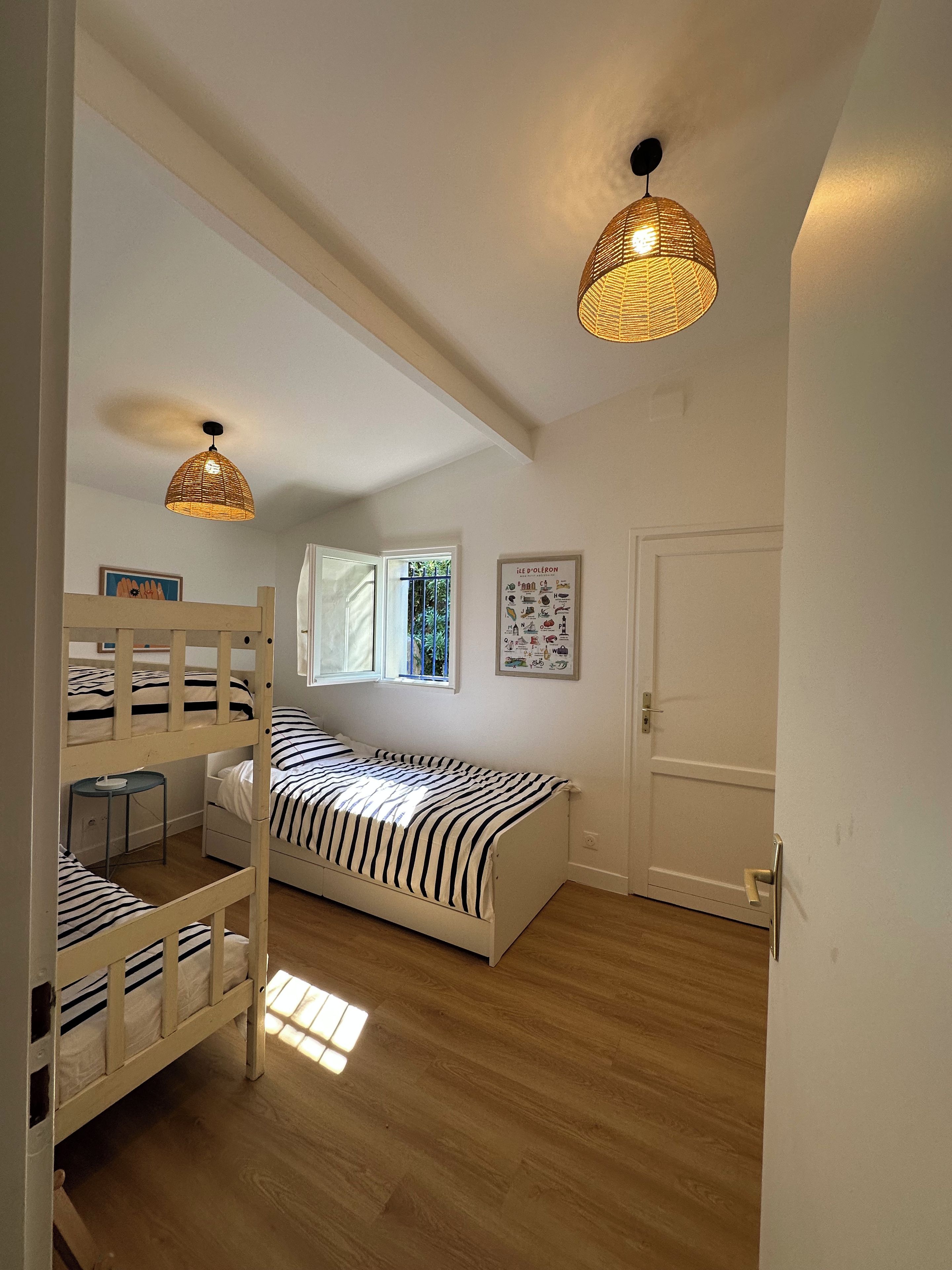 A room with bunk beds, a small table, and a hanging light fixture.