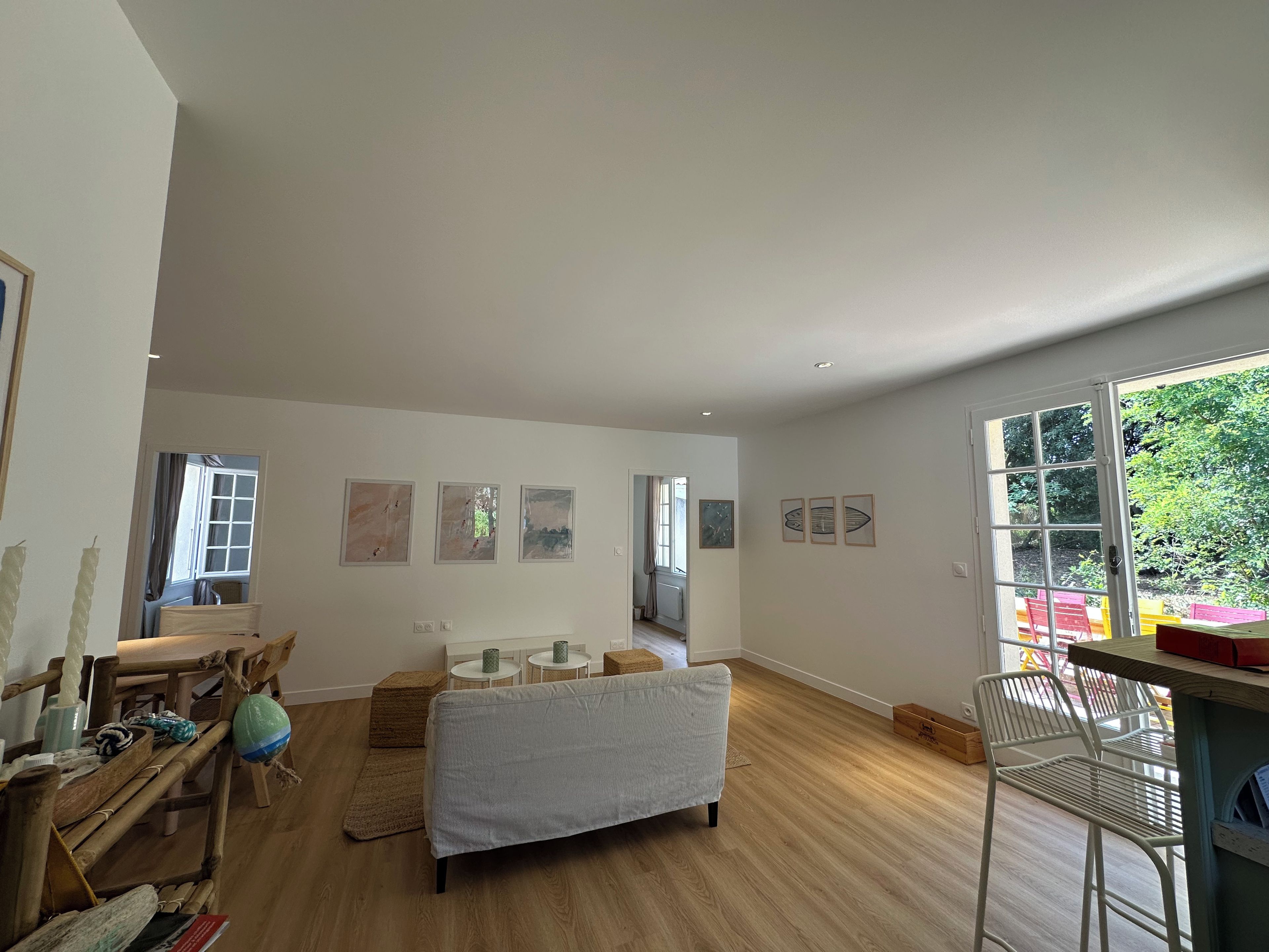 A spacious living area with a sofa, a dining table, and a chair. There are several framed artworks on the walls.