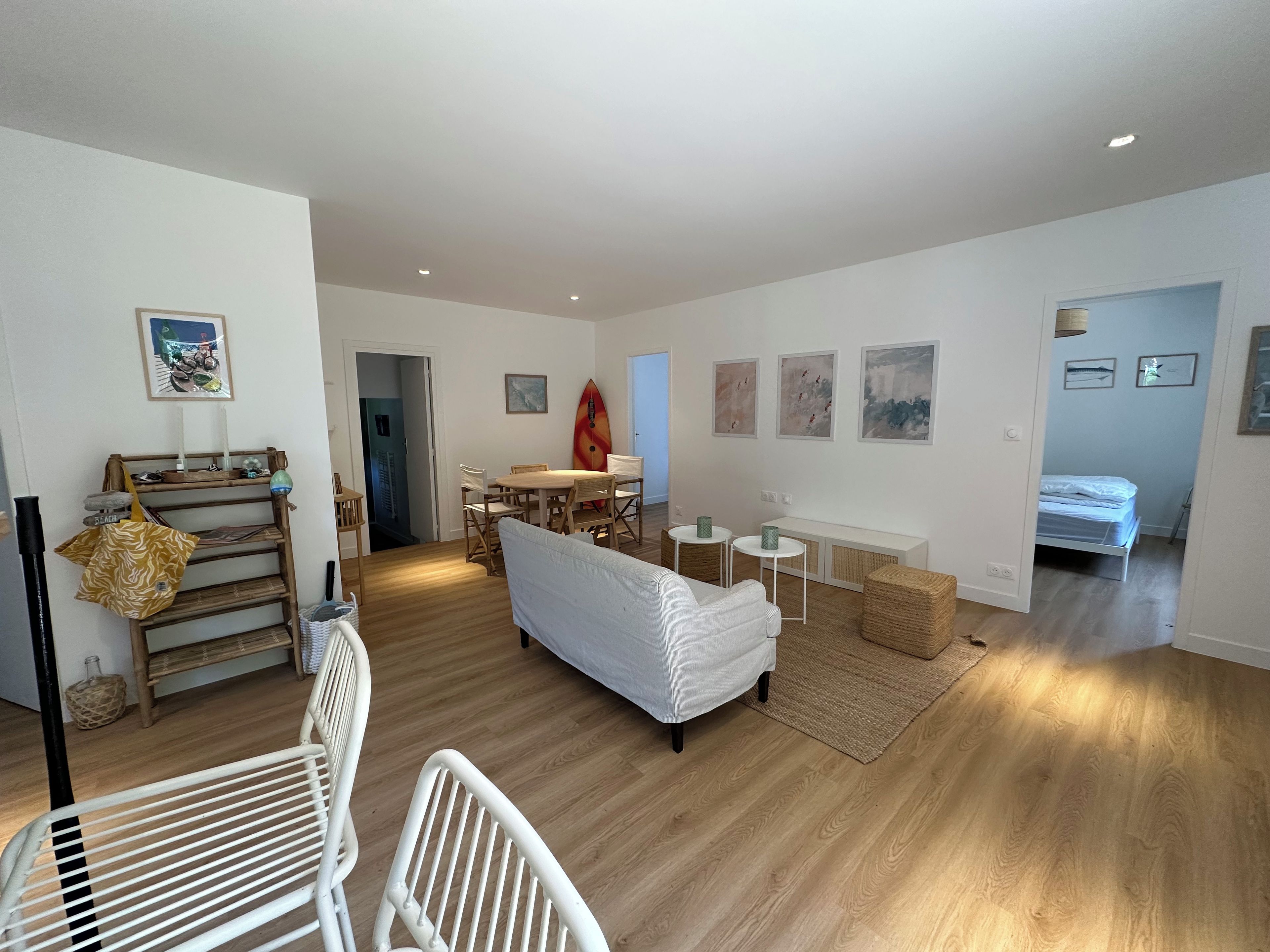 A spacious living area with a sofa, a dining table, and a surfboard.