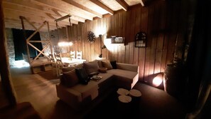Una stanza accogliente con arredamento in legno, un divano, un tavolo e un lampadario.