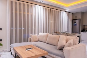 A modern living room with a sofa, a coffee table, and a dining area with a table set for two. - Villa Savaya 1 Antalya (Kaş)