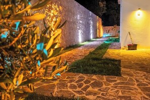 A nighttime outdoor area with a stone pathway, a wall with a light, and a bucket with a mop. - Villa Savaya 1 Antalya (Kaş)