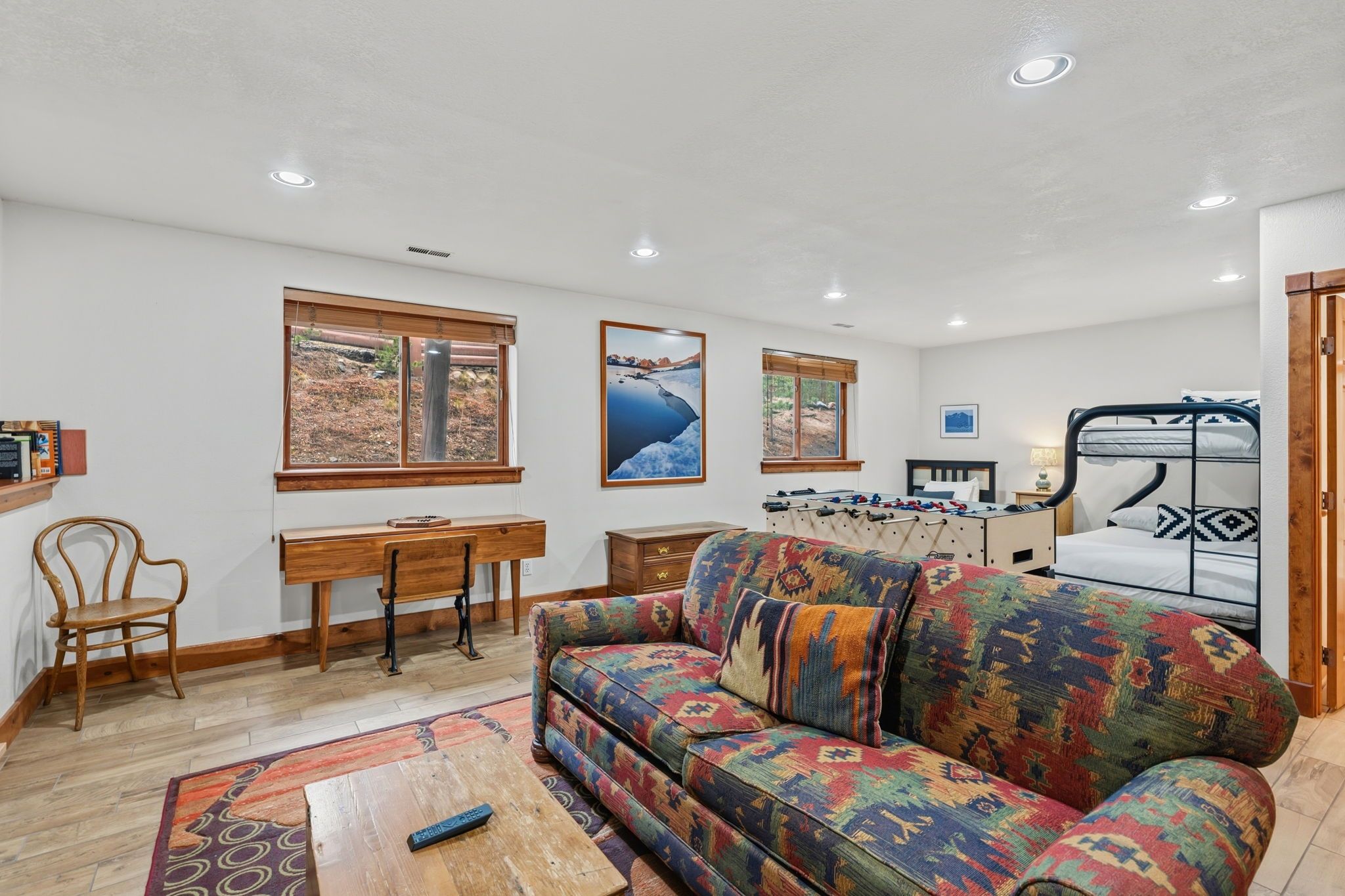 A living room with a sofa, a coffee table, a wooden chair, a desk, and a futsal table.
