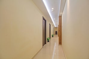 Un pasillo de hotel con piso de baldosas brillantes, puertas de madera e iluminación empotrada en el techo.