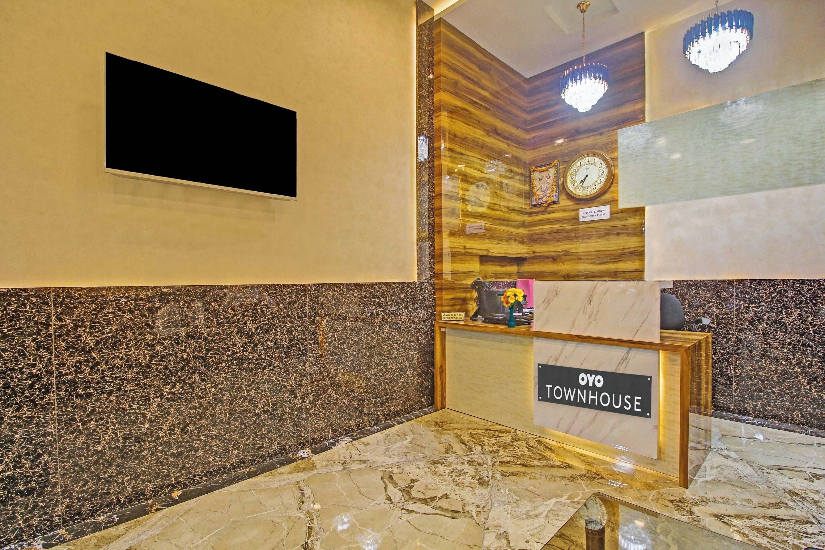 Uma mesa de recepção com uma placa indicando 'OYO TOWNHOUSE' e um relógio acima.