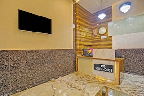 A reception desk with a sign reading 'OYO TOWNHOUSE' and a clock above it.