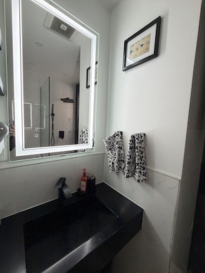 A bathroom with a black sink, a large mirror, and a framed picture on the wall. - Perfect 1-bedroom apartment in peaceful Hoboken (Hoboken)