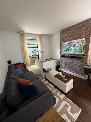 Ein modernes Wohnzimmer mit einem Ecksofa, einem Couchtisch und einer Ziegelwand als Blickfang.