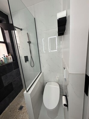 Ein modernes Badezimmer mit Duschkabine aus Glas, Toilette und Handtrockner.