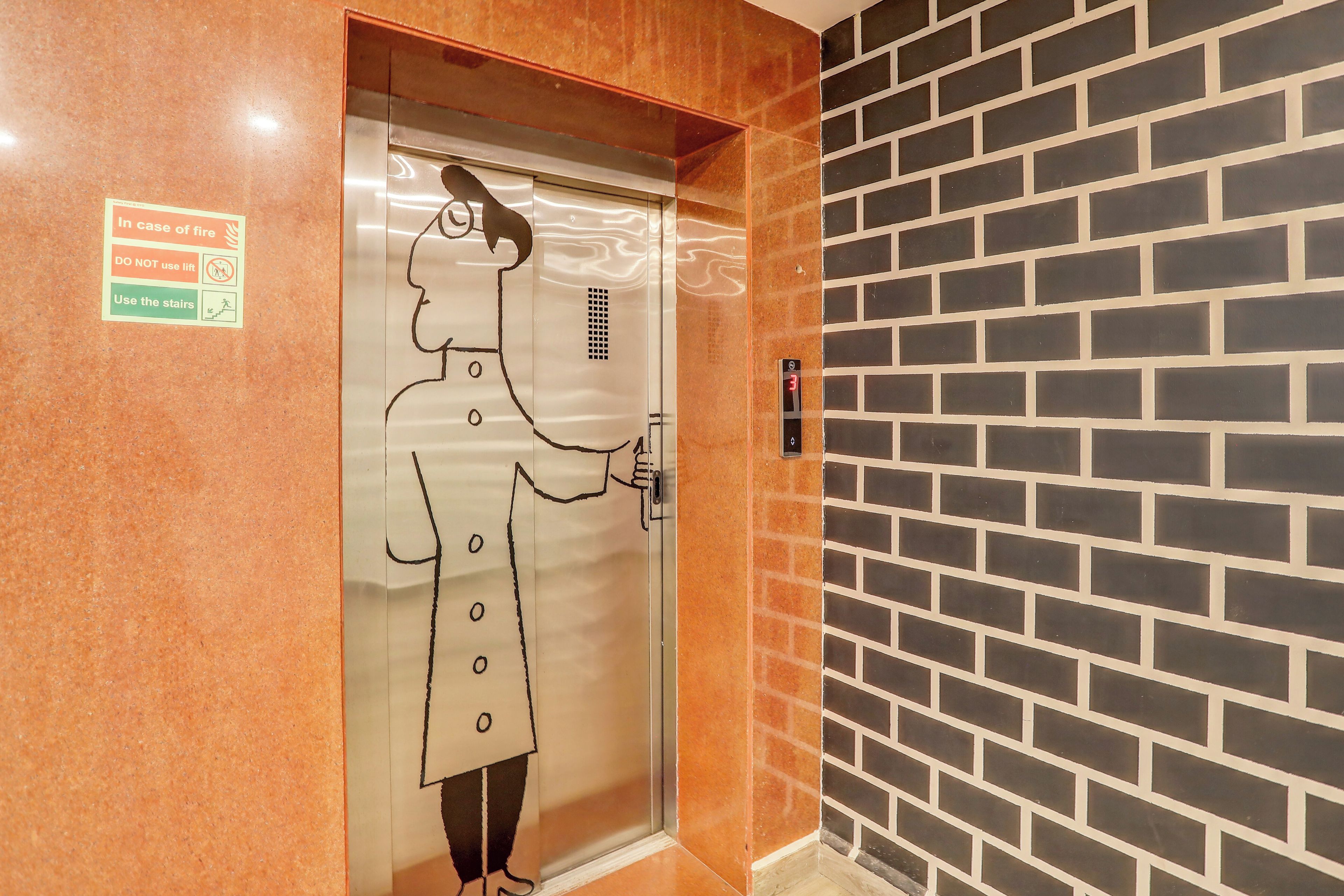 An elevator with a safety sign and a person holding a phone.