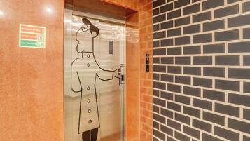 An elevator with a safety sign and a person holding a phone.