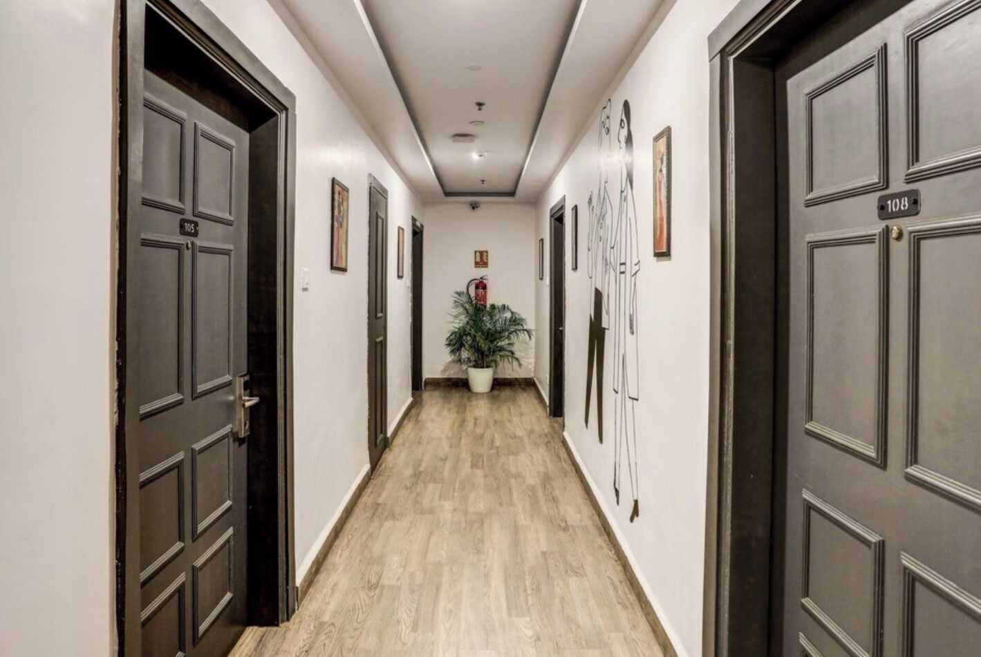 A hallway with dark wooden doors, numbered plaques, and framed artwork on the walls.