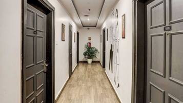 A hallway with dark wooden doors, numbered plaques, and framed artwork on the walls.