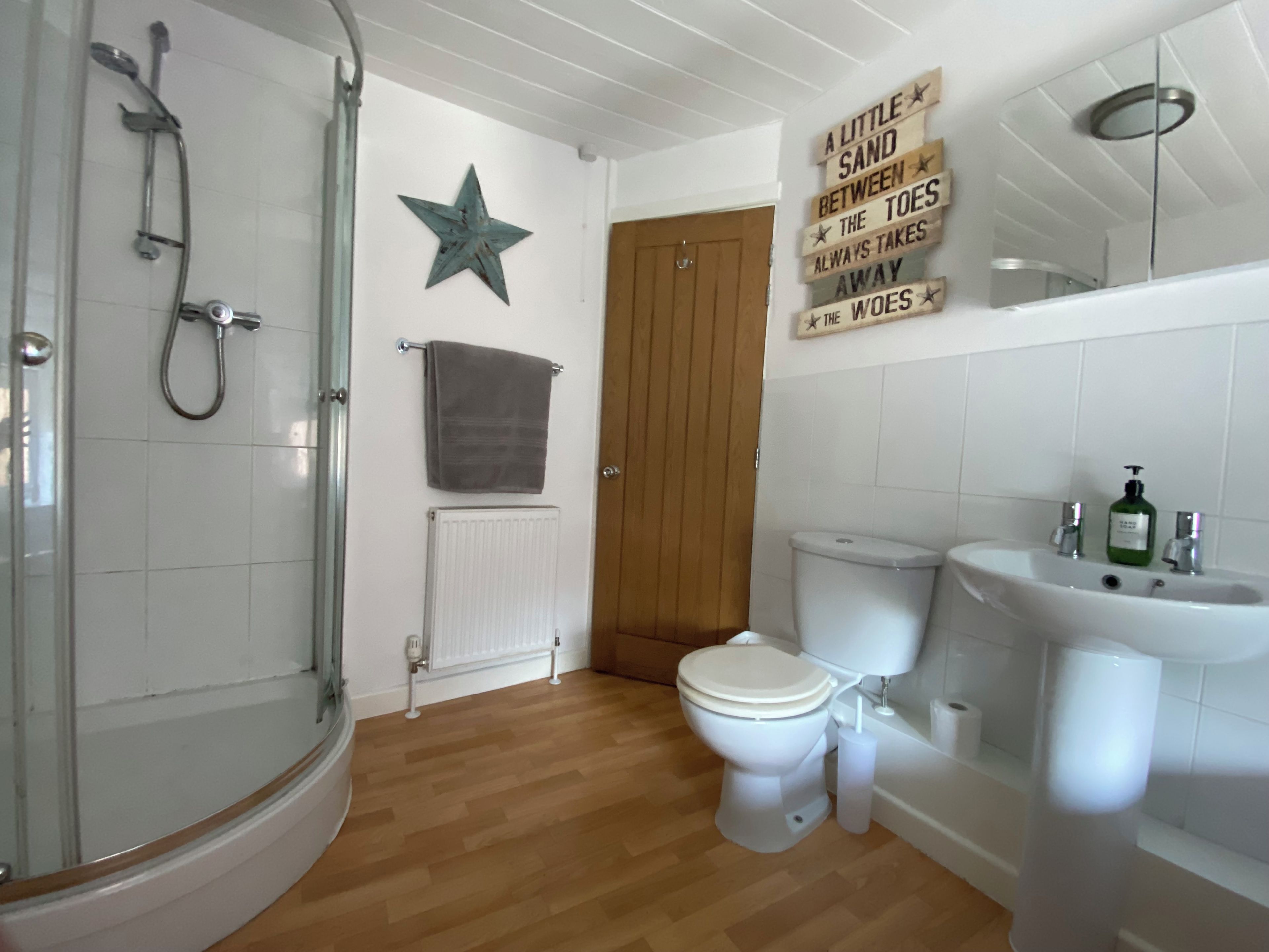A bathroom with a shower, toilet, sink, and a star decoration on the wall.