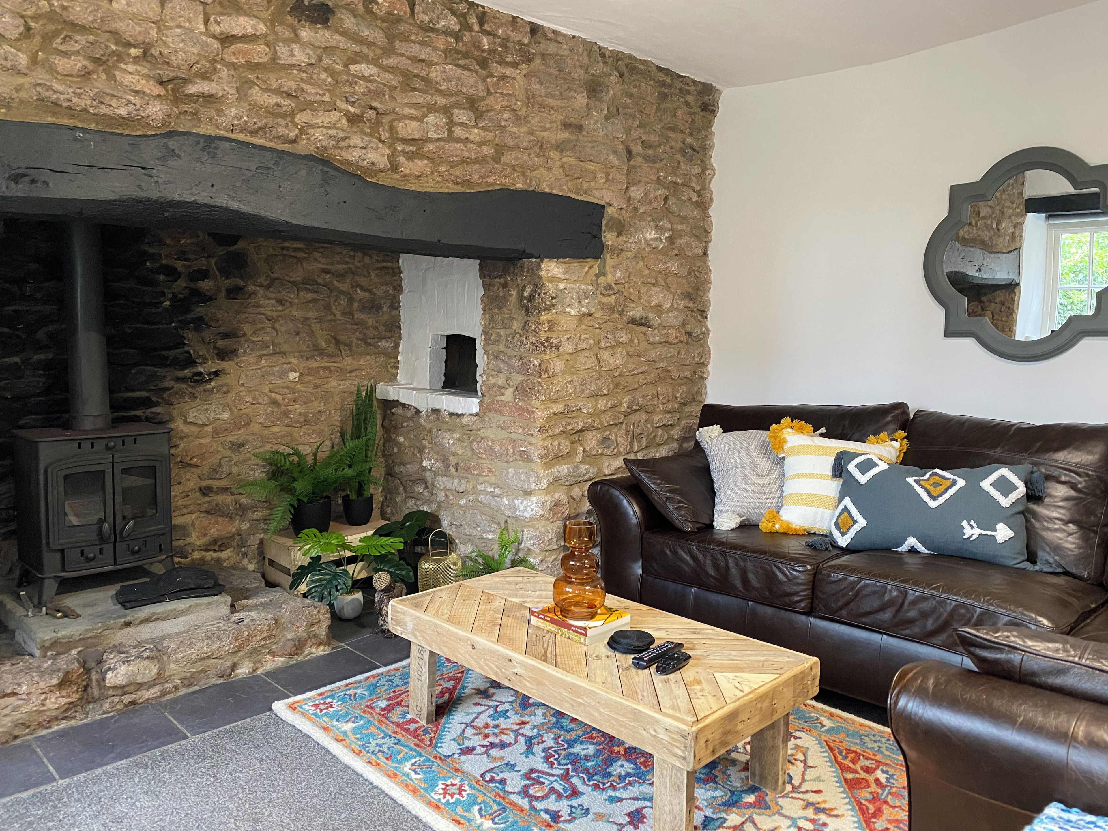 A cozy living room with a stone wall, a fireplace, a leather sofa, and a coffee table.